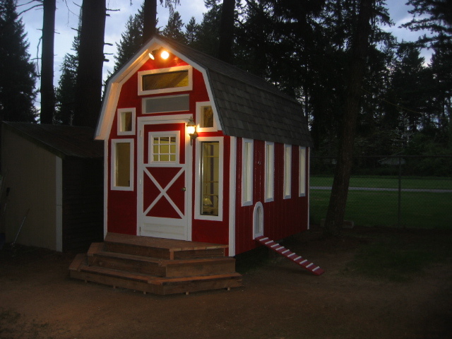 large barn style chicken coop plan with red exterior and porch lighting for backyard flock