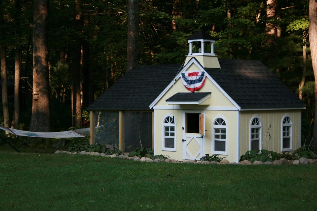 large backyard chicken coop designed like a small schoolhouse building with cupola and windows